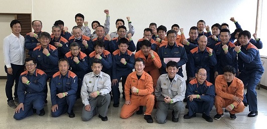 消防士の方々がいろいろなポーズをとり記念撮影をしている写真