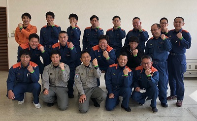 3列に並んだ消防士の方々がガッツポーズをして記念撮影をしている写真