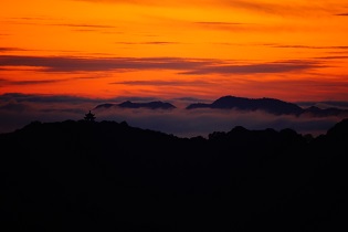 空が明るくなりだした山に雲海が見えている写真