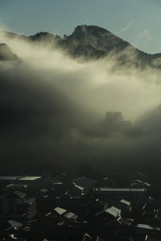 山あいに発生した大量の霧と、その山のふもとにある霧がかかっていない住宅地を写した作品