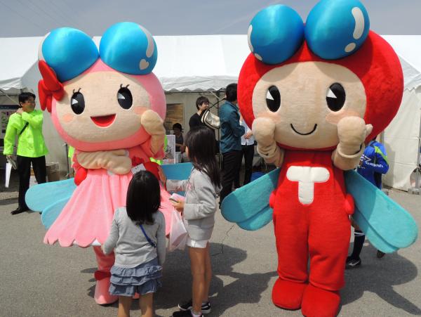 子どもたちとたわむれる赤とんぼくんとあかねちゃんの写真
