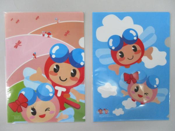 野原を飛ぶ小さな赤とんぼと、大きな赤とんぼくんとあかねちゃんの絵が載ったクリアファイルと、青空を飛ぶ赤とんぼくんとあかねちゃんの絵が載ったクリアファイルの写真