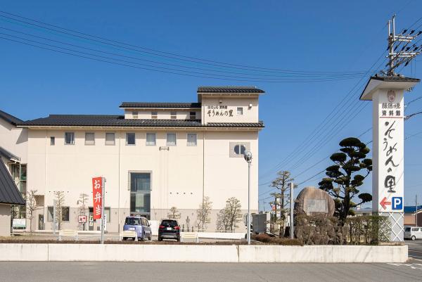 道路沿いに「揖保乃糸資料館そうめんの里」と書かれた大きな看板が設置された敷地内に白壁の建物が建っている写真