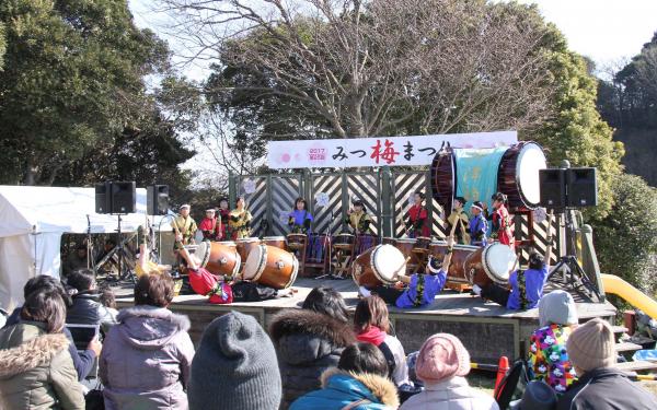 ステージの上で和太鼓叩きを披露する人々と、その演奏を聴く観客たちを斜め後方から写した写真
