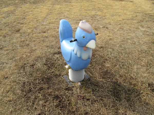 公園の芝生の上にある、水色のトリのスプリング遊具の写真