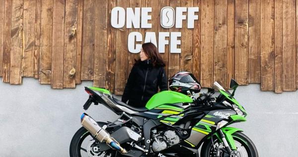 黄緑色のバイクの後ろに横を向いて立っている白石さんの写真