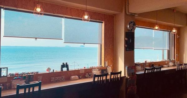 カフェのカウンターの窓から海が見えている風景写真