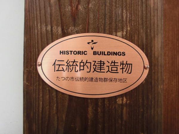 銅板で楕円形をした伝統的建造物表示銘板を正面から写した写真