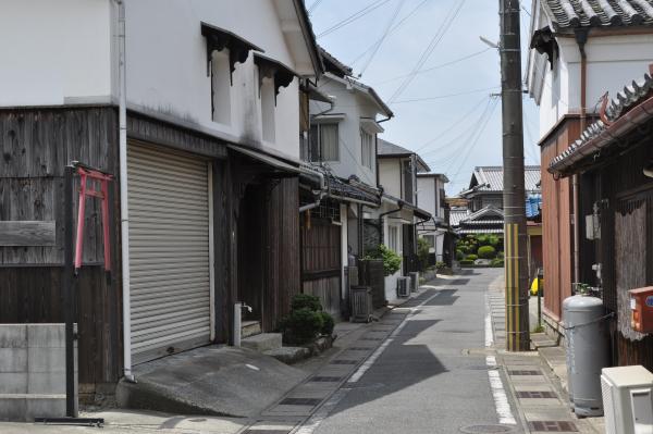 2階部分の外壁が白い建物が道路両脇に建ち並んでいる様子を写した写真