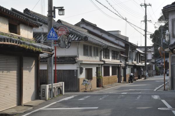 道路の中央に橋の名残があり、奥に並ぶ豪壮な商家の写真