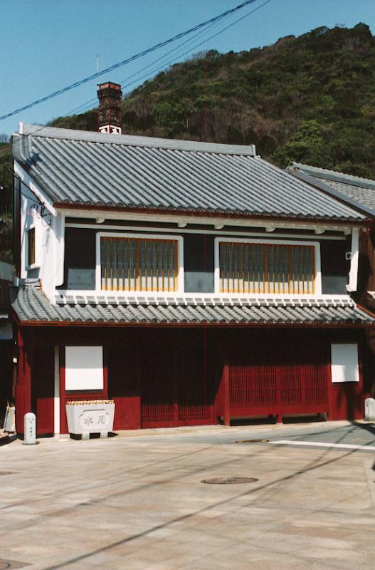 2階が白で縁どられた窓枠、1階は朱色の格子づくりの「たつの市かどめふれあい館」の写真