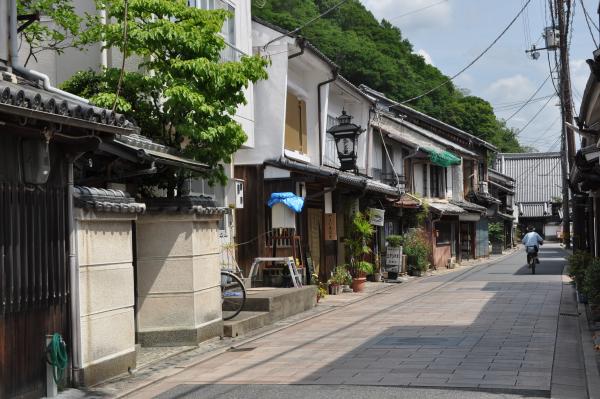 奥のお寺へ向かう石畳の通り沿いに白壁の町並みの店舗が建ち並ぶ上川原地区の写真