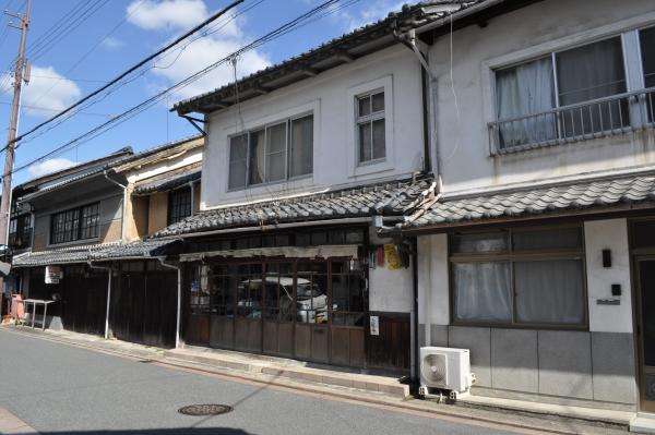 道路側に面した2階建ての和風造りの窓や玄関が残っている明治時代の町家の外観写真