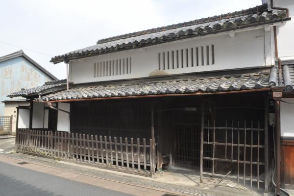 大きな蔵のような建物が木材のフェンスのようなもので囲われている写真