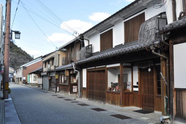 道路の右側に二階部分が伝統的な町家となっている町家が連なっている風景写真