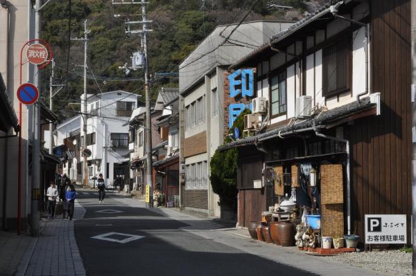 山の麓の細い道路沿いに、レンガ造りの建物や古民家が建ち並ぶ立町地区の写真