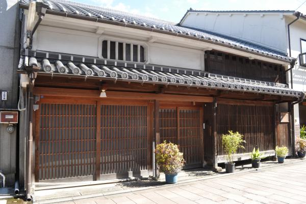 瓦屋根の厨子二階建ての家に、玄関と窓に木の格子がはめられている歴史を感じる家の外観写真