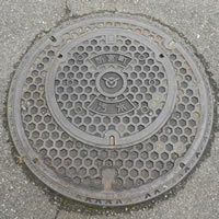 亀甲模様で中央に旧新宮町の町章、上に「新宮町」、下に「汚水」の文字が書かれたマンホールの写真