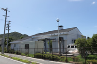 黒い屋根の下にポンプ場の名称が書かれている、白壁の揖保川流域下水道正條ポンプ場を道路から撮影した写真