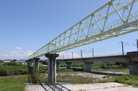 鉄道が通る高架橋と並行して、川を跨いで設置された揖保川流域下水道高架水管の写真