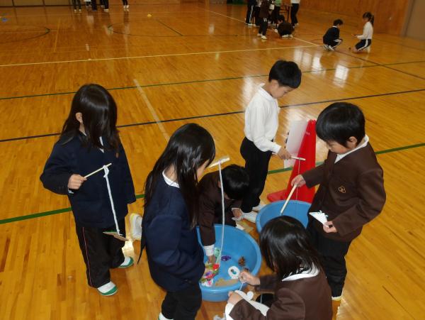 体育館でたらいに入ったものを紐をつけた道具で釣っている写真