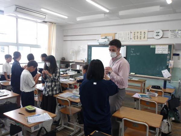 教室で二人ずつで向き合って立ち、話をしている写真