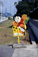 子どもの飛び出し注意を呼びかける安全坊やの看板が、道路わきに設置されている写真