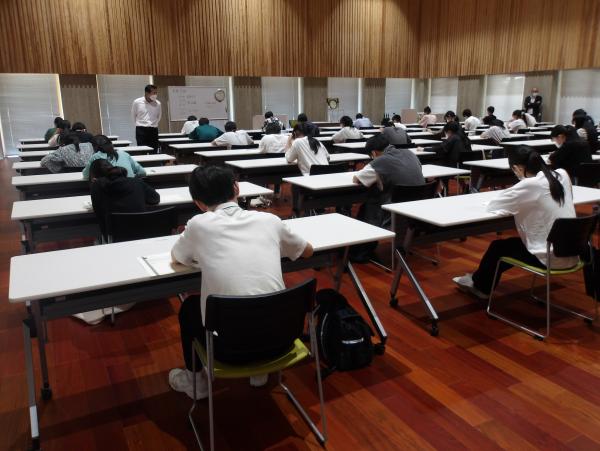 多くの受験生が長机に一人ずつ座り、問題を解いているところを後方から撮影した写真