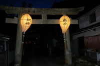 鳥居の両端に明かりのついた灯ろうが飾られている写真