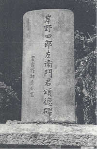 中央に縦書きで「岸野四郎左衛門君頌徳碑」と書かれた長方形の石碑のモノクロ写真