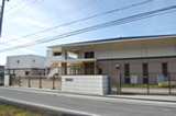 フェンスで囲まれた白とベージュ色の外壁で2階建ての龍野浄水場の建物外観を道路側から撮影した写真