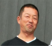 黒いシャツを着た短髪の高木さんをアップで撮影した写真