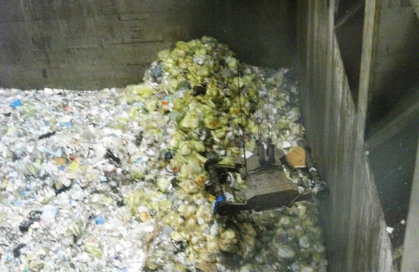 たくさんのごみがごみピット内にありクレーンでごみを持ち上げようとしている写真