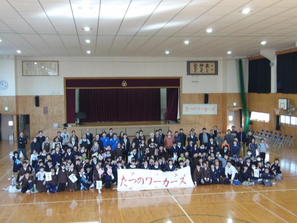 前列で「たつのワーカーズ」と書かれた幕を持ち、児童たちと講師の方々が集合して撮影した写真