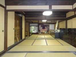 右側には箪笥が置かれ縦に長い広い和室になっている1階座敷の写真