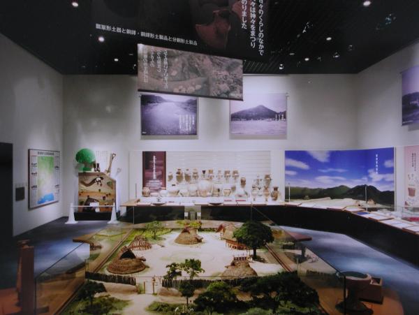 壁に様々な資料が貼ってあり、中央には古代集落の模型が作成されている室内の写真