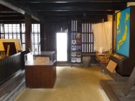 日本地図や船の模型、ガラスケースの展示品などが置かれた土間の写真