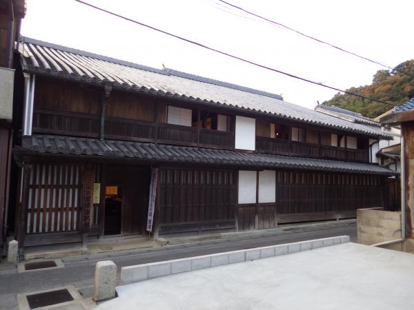 2階建ての木造の家に石瓦が長く配置された室津海駅館の写真