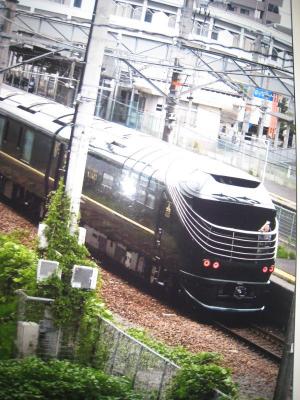 駅を出発したばかりの黒い電車を斜め上から撮影した写真