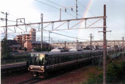 虹のかかった青空の下を颯爽と走る電車を撮影した写真