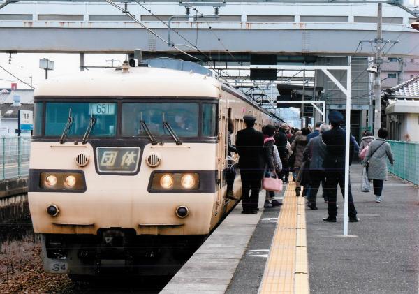 長い年月を走ってきて錆が目立つ電車から駅に降りる大勢のお客さんと駅員を撮った写真