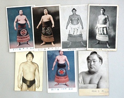 白黒写真やカラー写真の7枚の力士像絵はがきが置かれている写真