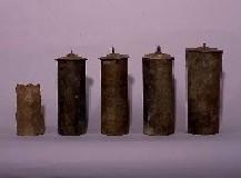 細長い筒形の蓋が付いた経筒が5個並べられた写真