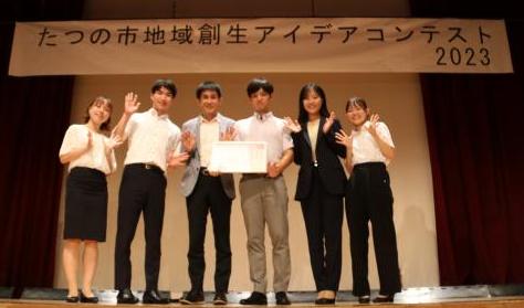 審査員特別賞を受賞した大阪大学赤井研究室の皆さんが、舞台の上に立ち賞状を持って横一列に並んでいる写真