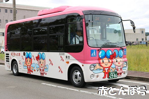 車体の半分から上がピンク色でその下にたつの市のキャラクター赤とんぼくんとあかねさんがデザインされたコミュニティバス赤とんぼ3号を左前方から写した写真