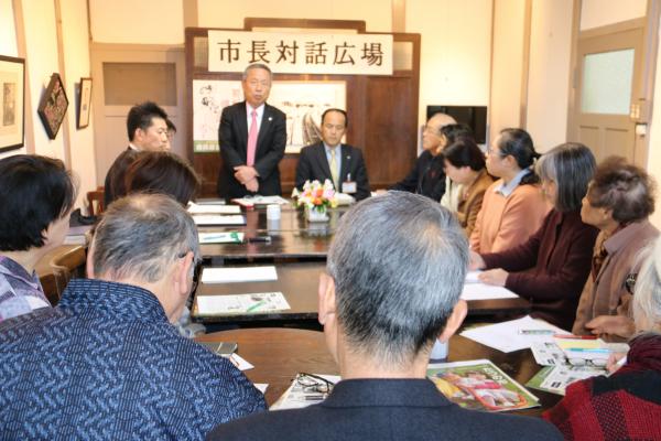 席に座っている参加者達が、前方で立ち話をしている市長の話を聞いている市長対話広場の写真