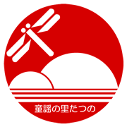 赤地の丸の中に白色で山とトンボが描かれてる童謡の里シンボルマーク