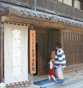 たつの市立室津海駅館と書かれた木製看板が設置された入り口から母親と女の子が入場しようとしている写真