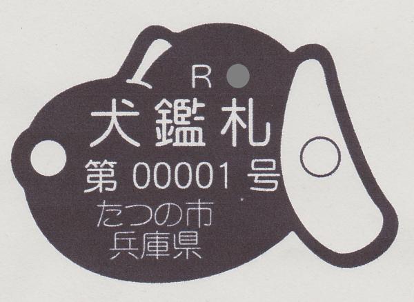 こげ茶色の犬の顔の形をした犬鑑札の写真
