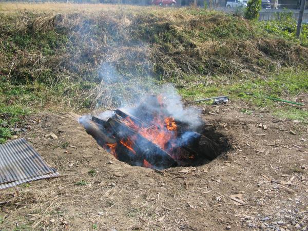 広場で地面に穴を掘ってその中でゴミを焼いている写真